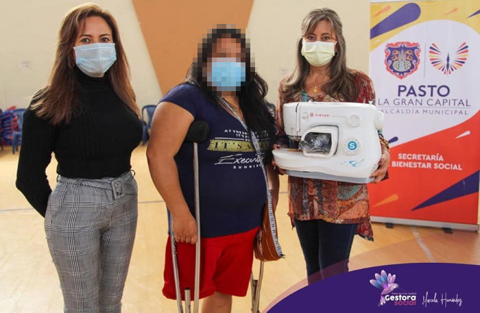 Ciudadana beneficiaria de espacios para la inclusión recibiendo máquina de coser
