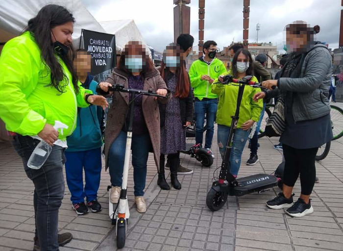 Peronas en feria de movilidad usando patinetas eléctricas